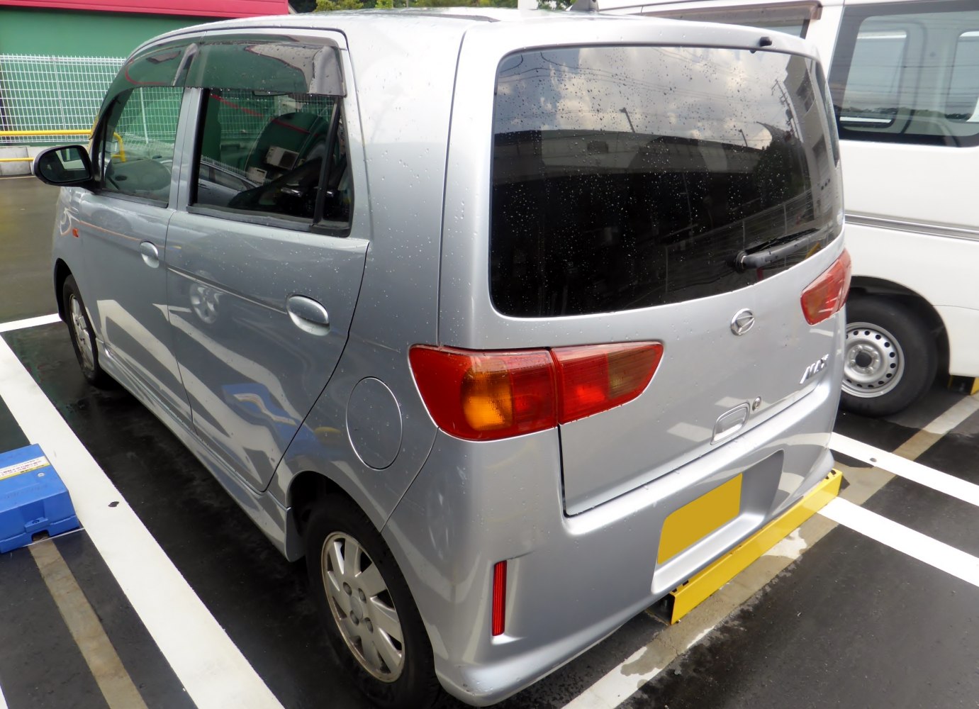 Compact hatchback rear with tail lights and rain droplets