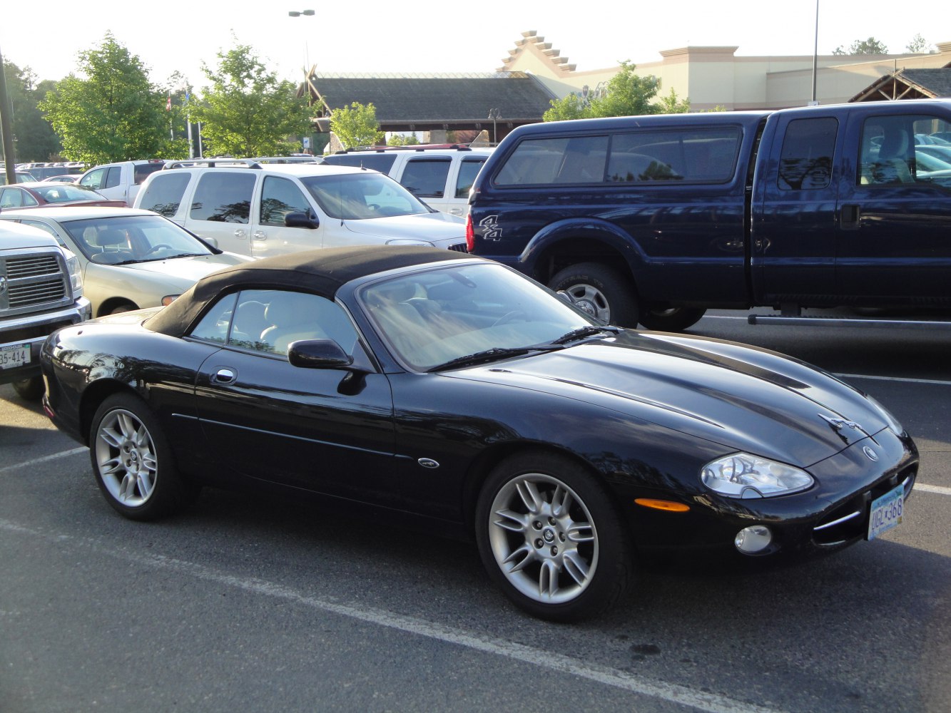 Black convertible with soft top and alloy wheels in parking lot