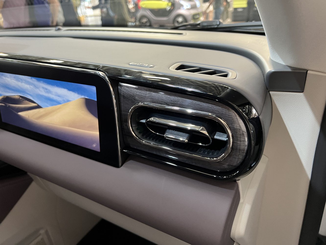 Close-up of elegant dashboard air vent with wood trim and digital infotainment screen