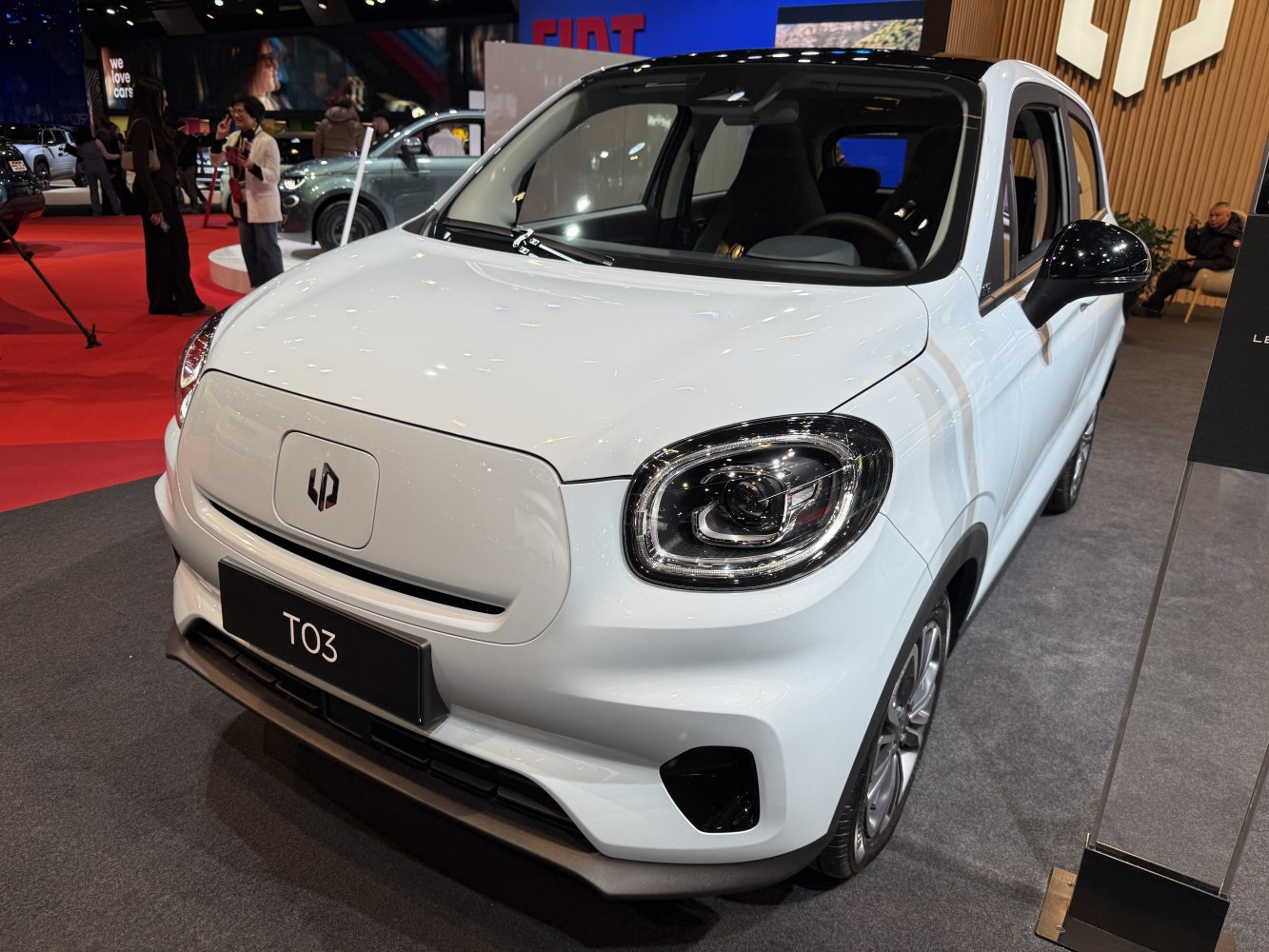 Front exterior of a compact electric car with distinctive headlights and smooth grille.