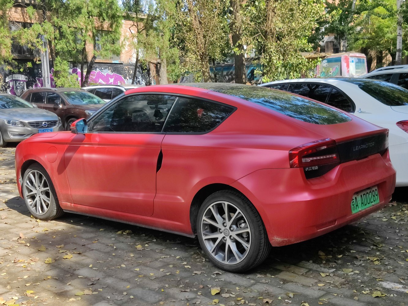 Matte red electric coupe rear side with sleek taillights and alloy wheels