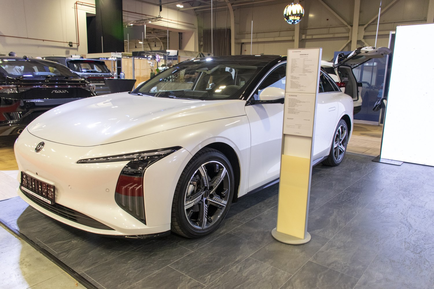 Front left view of a white modern vehicle with aerodynamic design and sleek headlights.