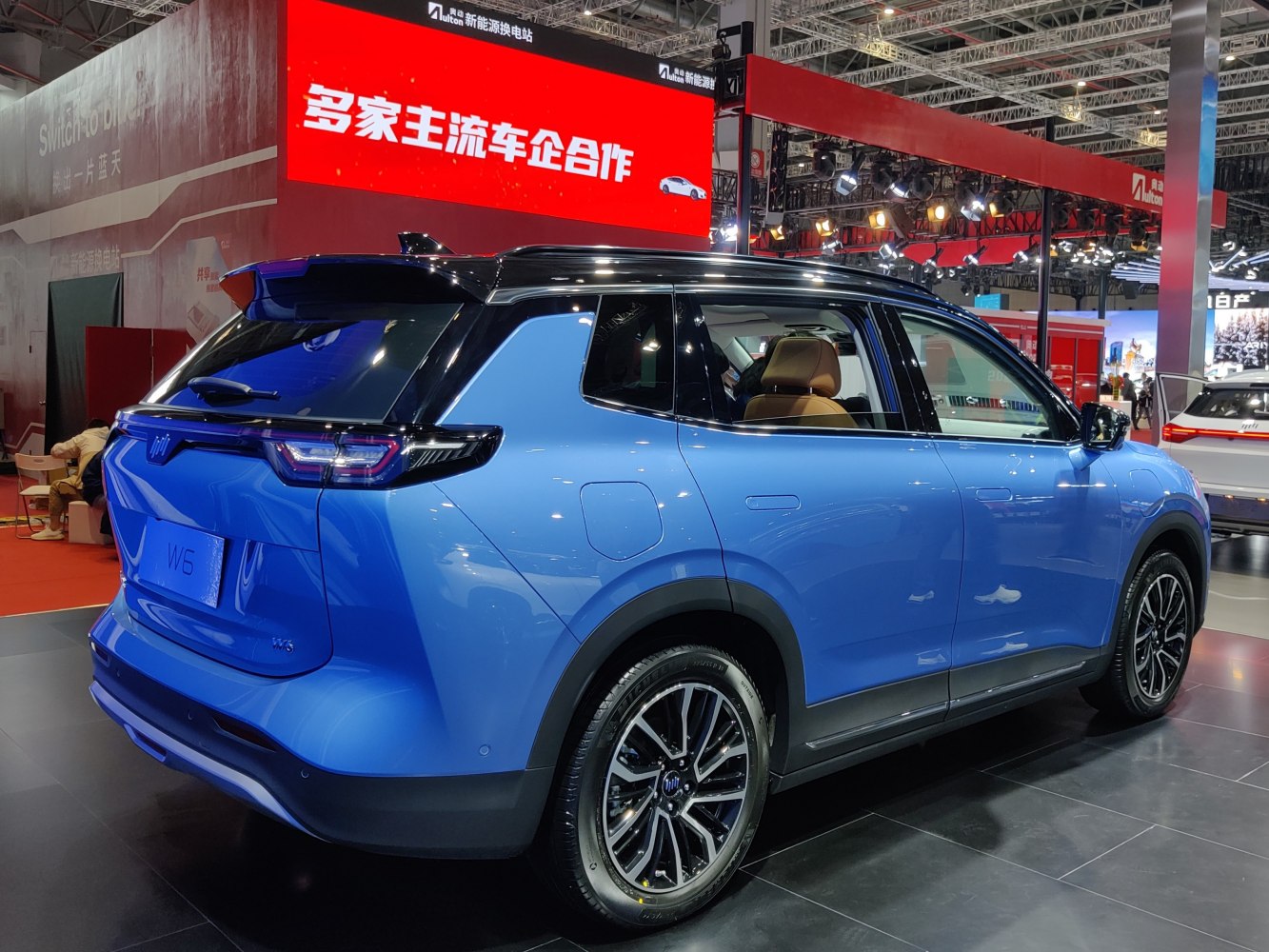 Blue electric SUV rear side view with alloy wheels and roof spoiler