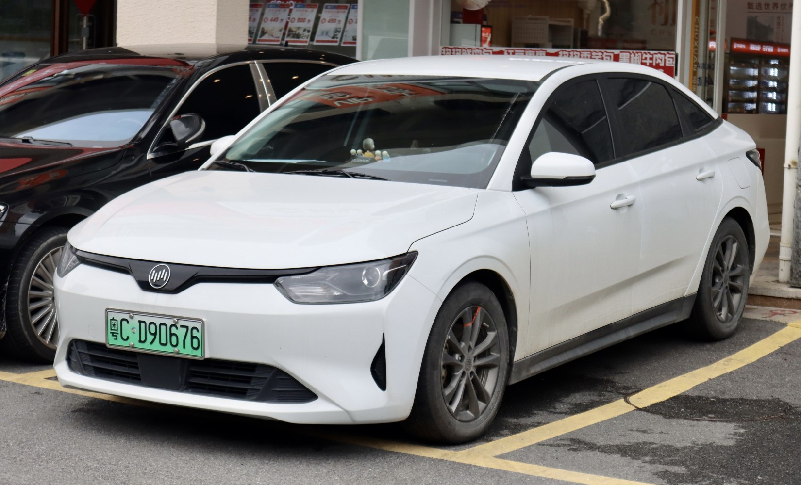 Front and side view of a sleek white electric sedan with distinctive headlights.