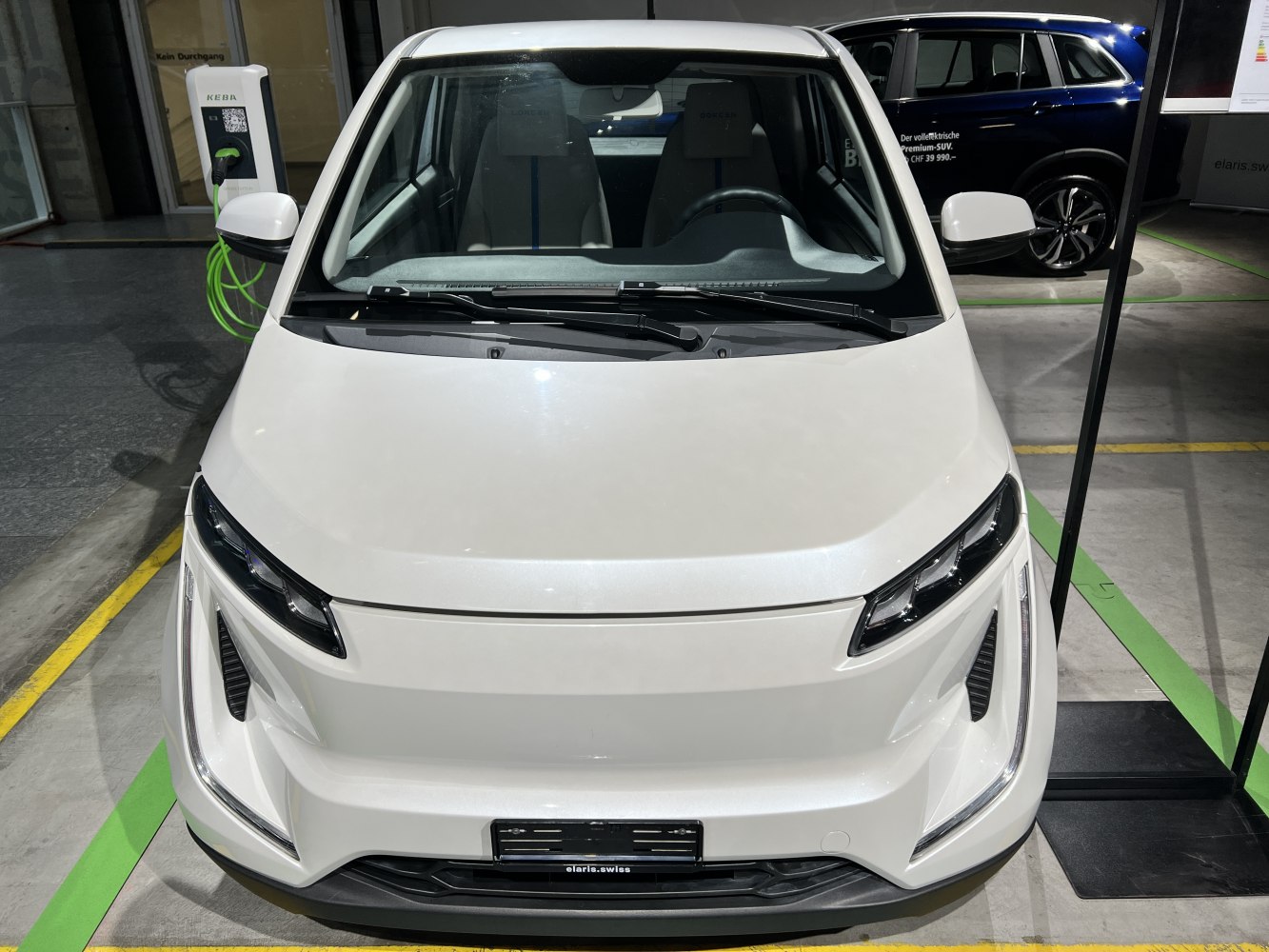Compact electric vehicle front with sleek headlights and aerodynamic hood