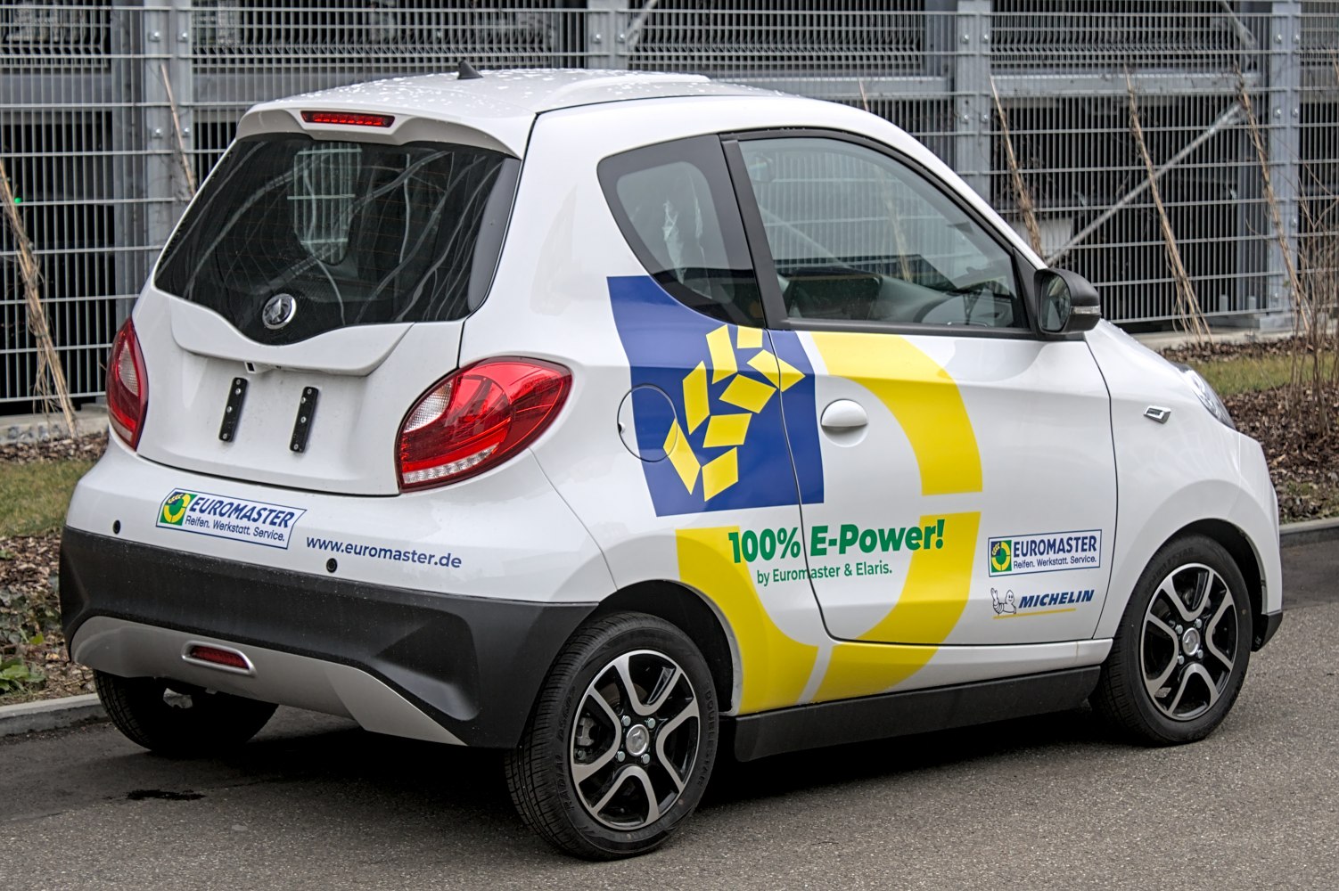 Rear side view of electric compact car with promotional branding
