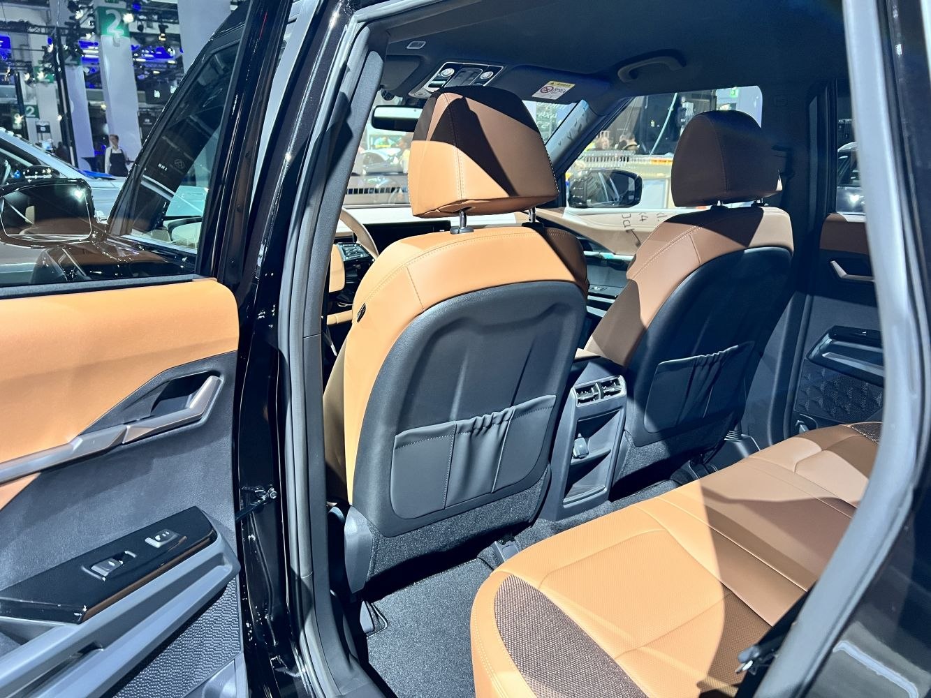 Spacious brown leather rear seating with detailed door panel and modern controls.