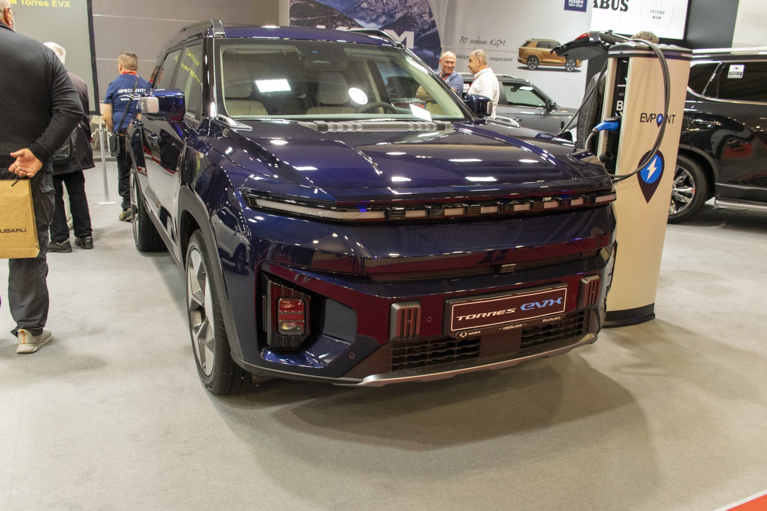 Front view of SUV with sleek headlights and connected EV charging station