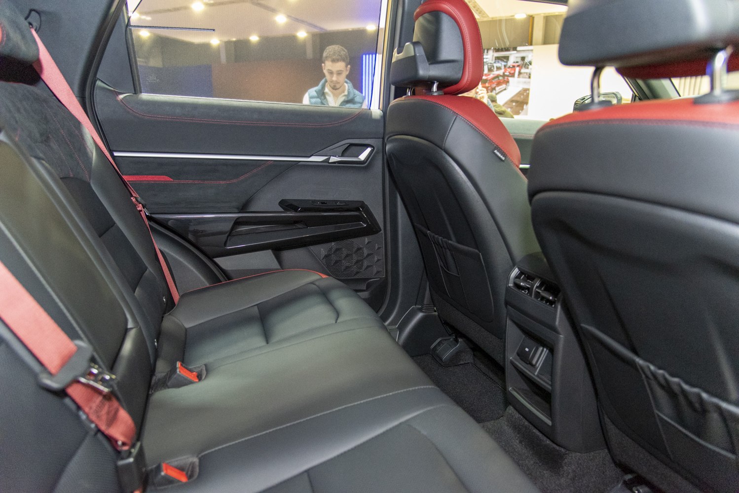 Rear black leather seats with red accents and modern door panel.
