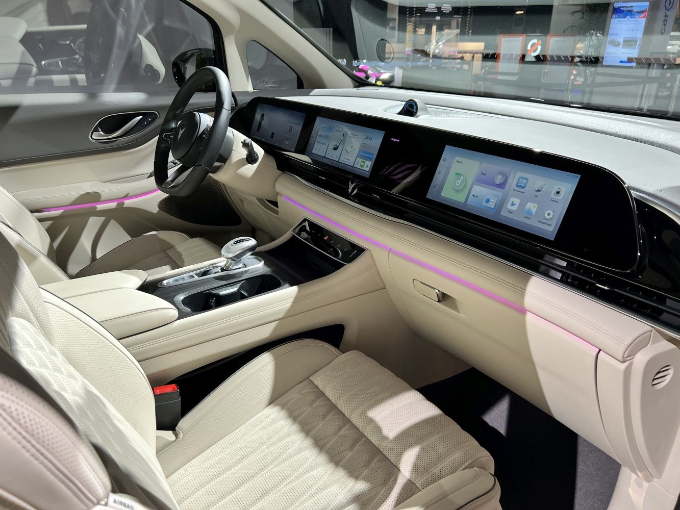 Dual wide touchscreen dashboard with ambient lighting in modern beige interior