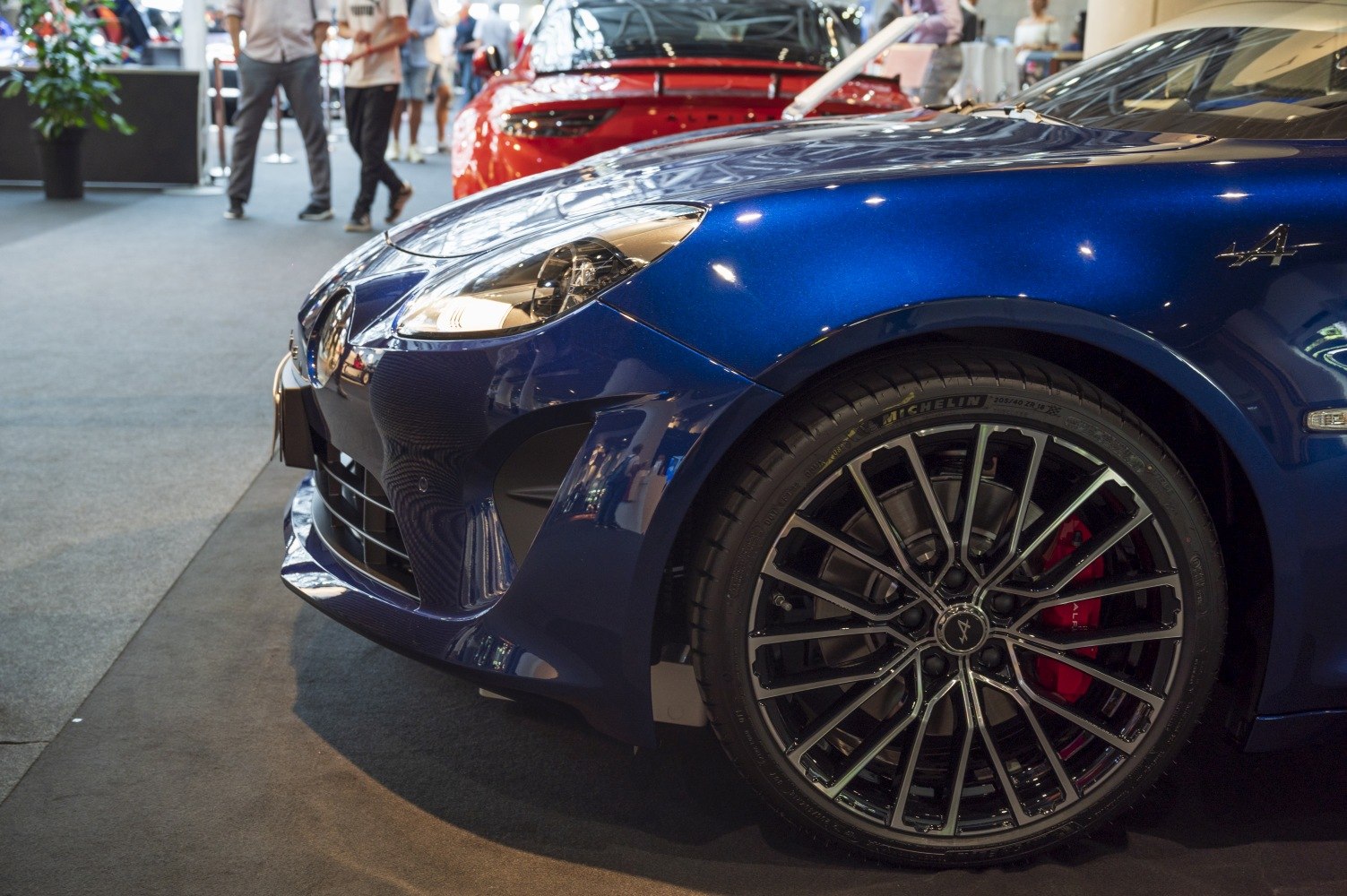 Close-up of front headlight and alloy wheel with red brake caliper.