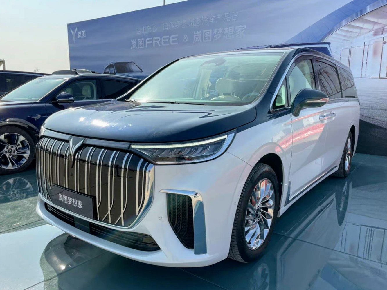 Luxury minivan front with large vertical chrome grille and slim LED headlights