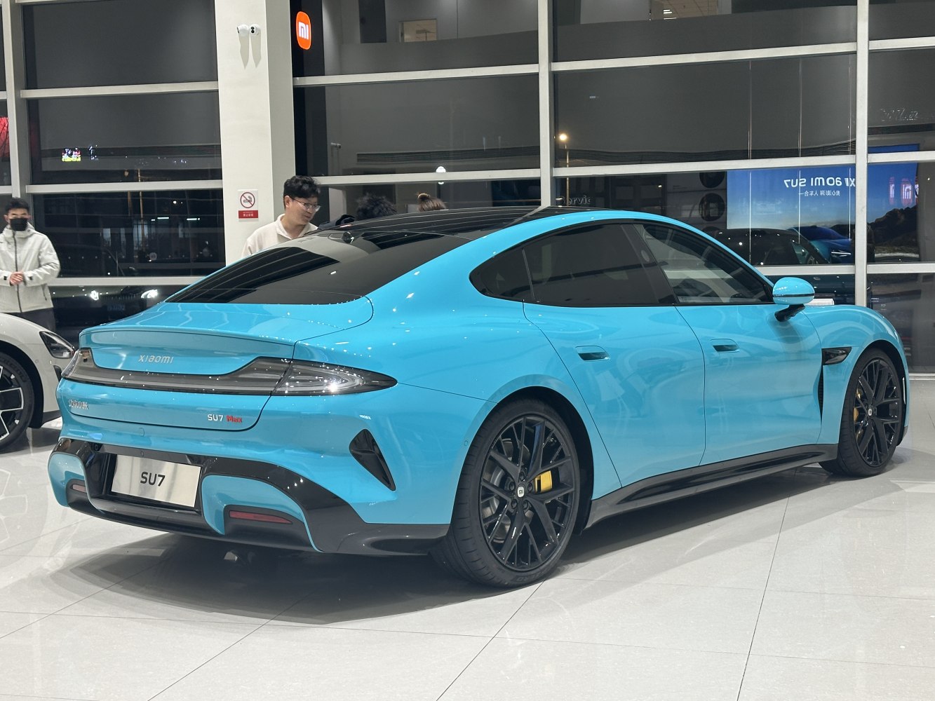 Rear side view of sleek blue electric sedan with black wheels