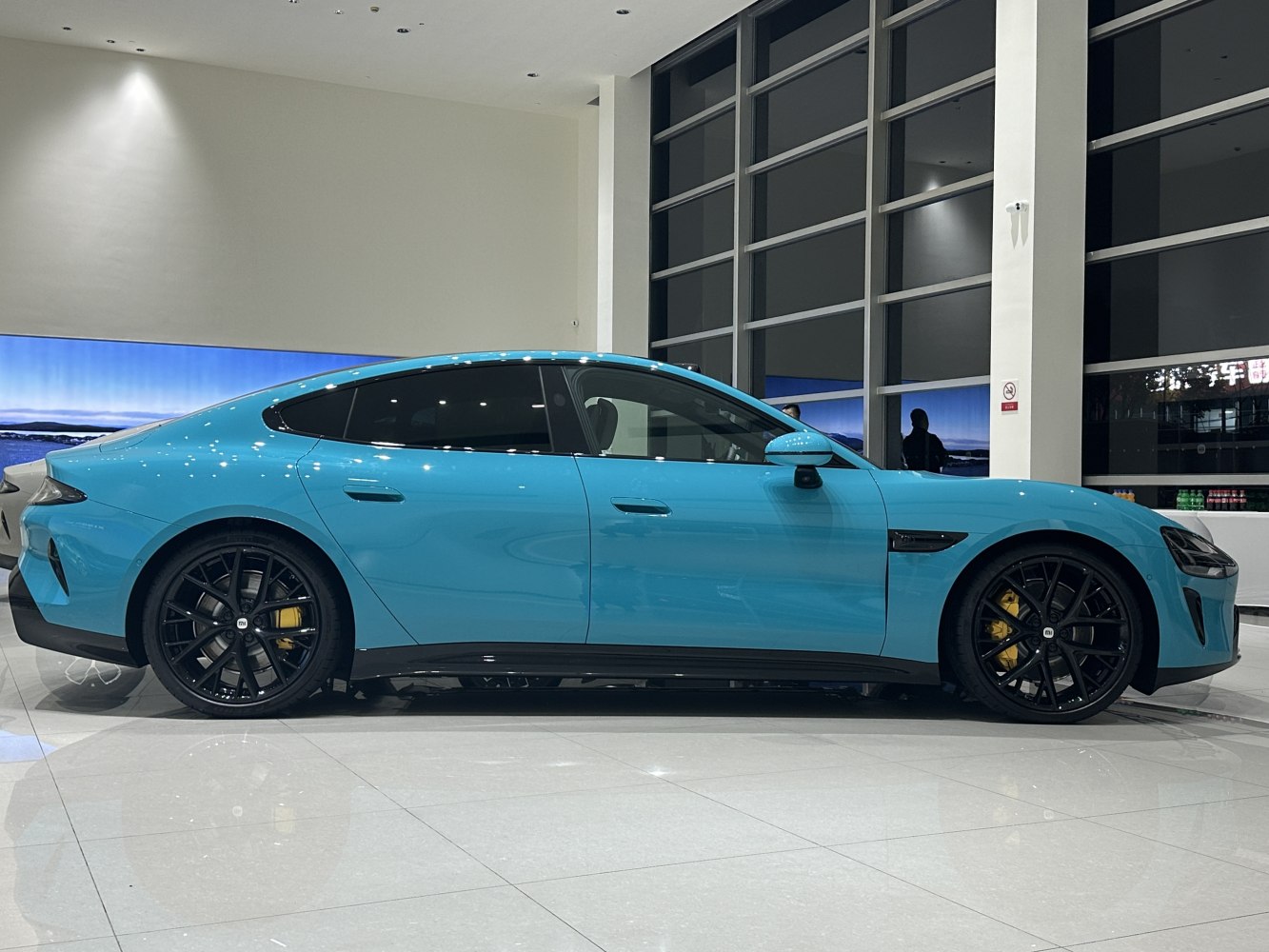 Electric sedan side view with black alloy wheels and yellow brake calipers