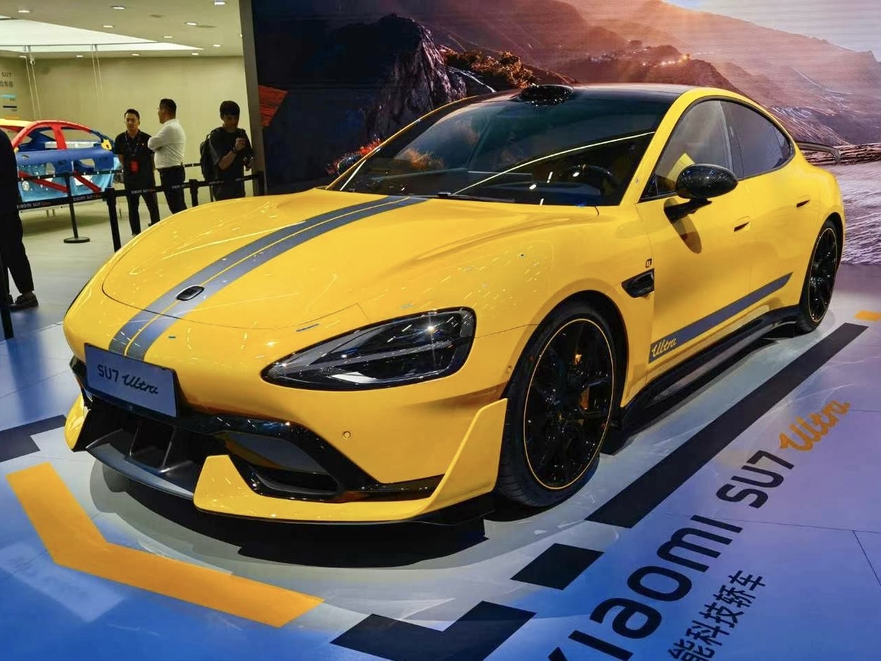 Yellow sporty sedan with gray racing stripes and aerodynamic design
