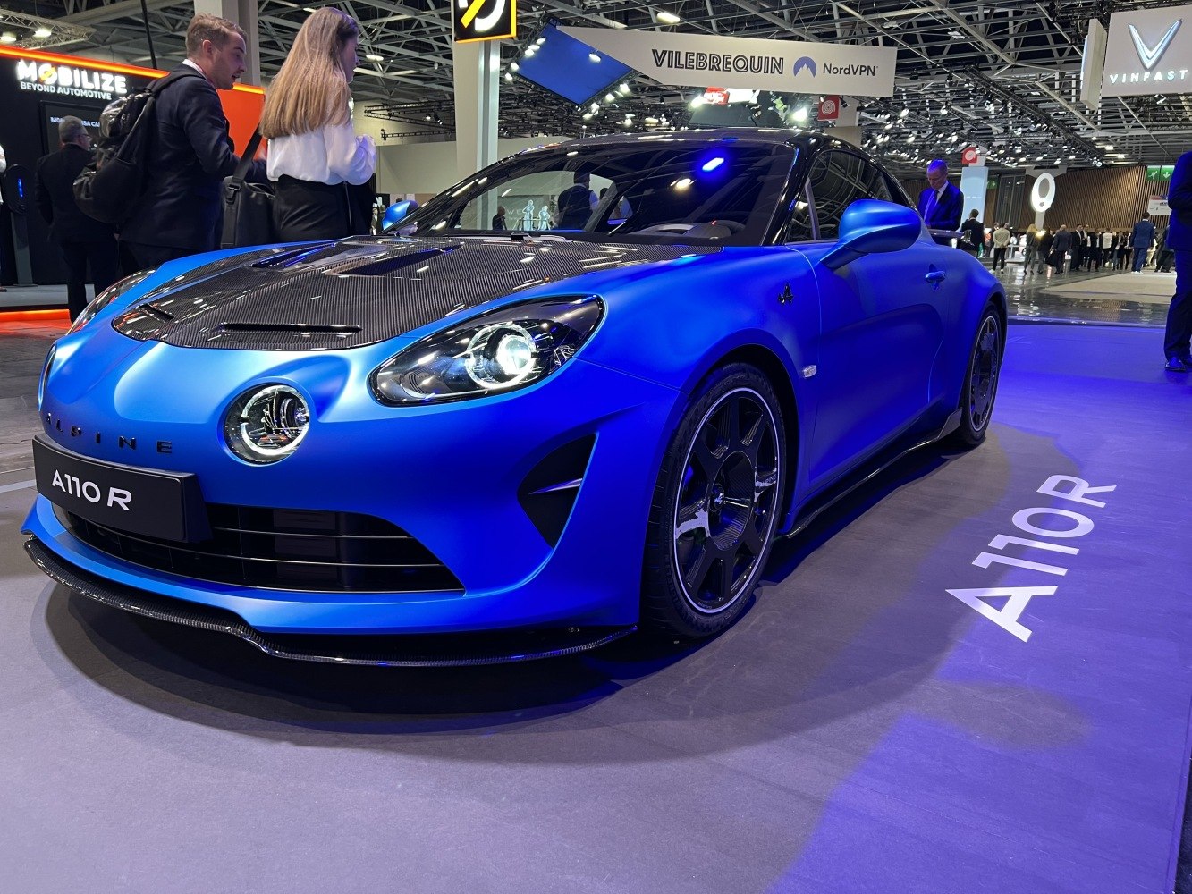 Matte blue sports coupe with carbon fiber hood and distinctive front lighting