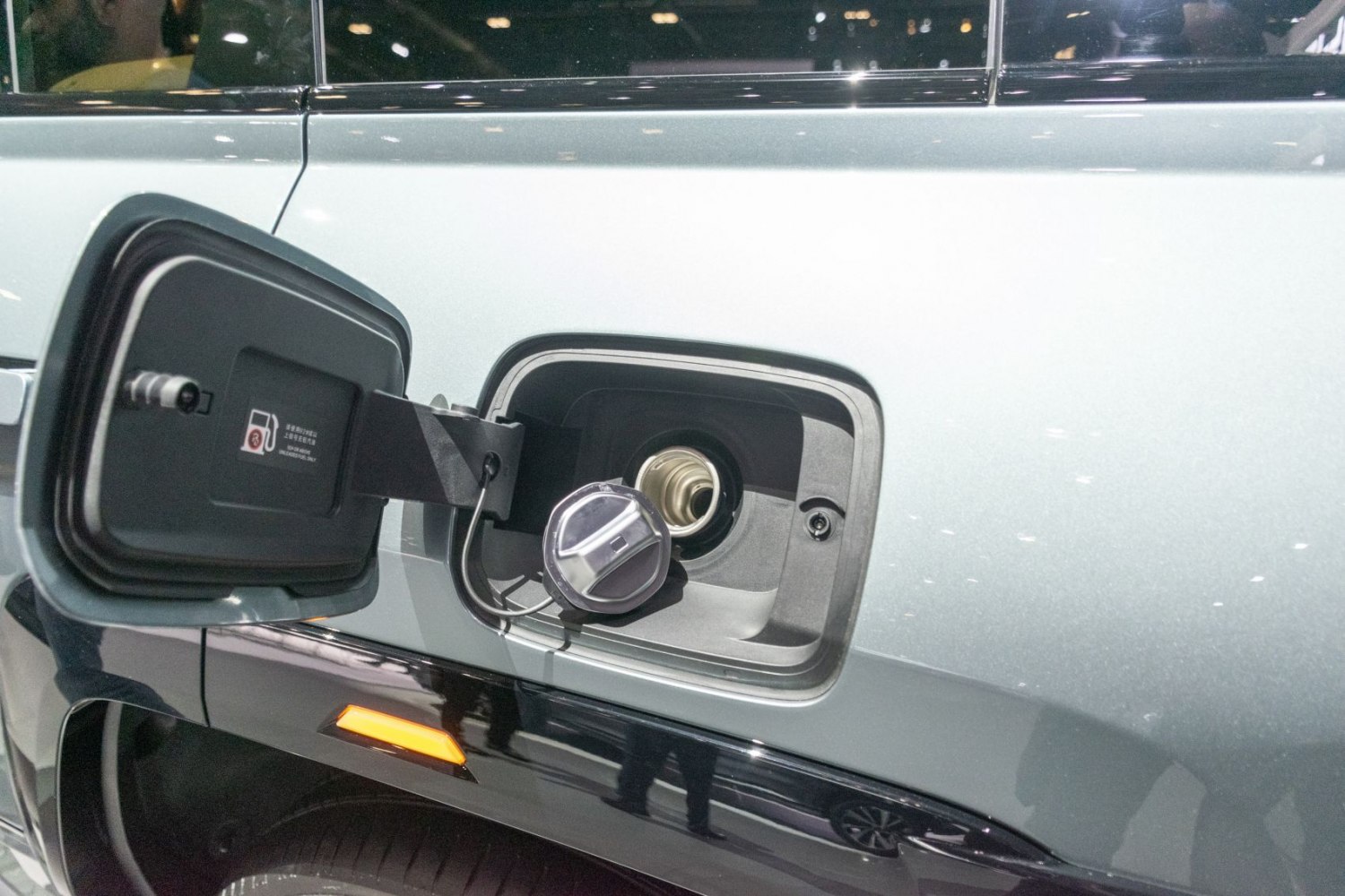 Fuel cap and fuel filler neck with attached cap on a vehicle