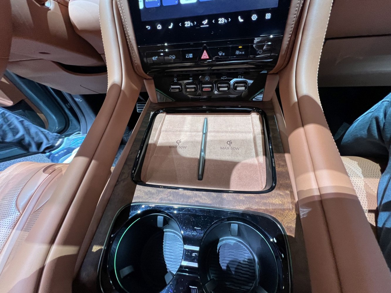 Center console with dual 50W wireless charging pads and cup holders in brown leather interior