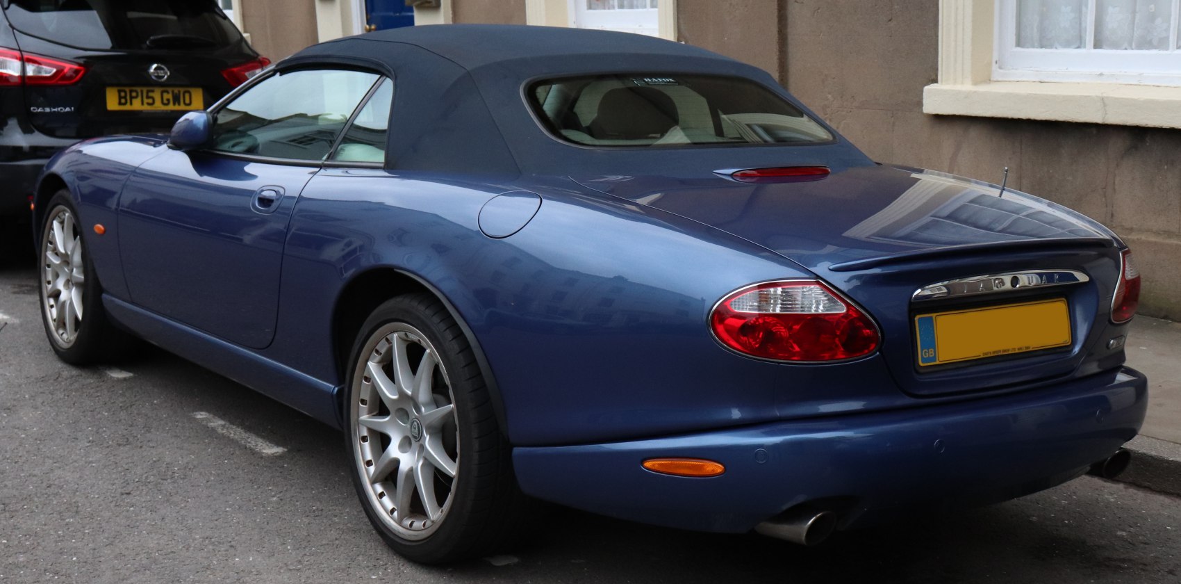 Rear-side view of a blue convertible with soft top roof and sporty alloy wheels