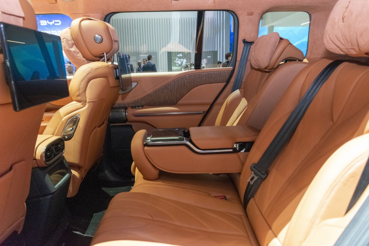 Luxury tan leather rear seating with entertainment screens and armrest