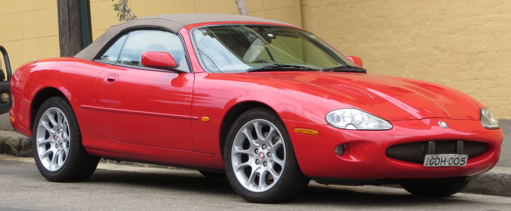 Red convertible with soft top, alloy wheels, sporty front-side view
