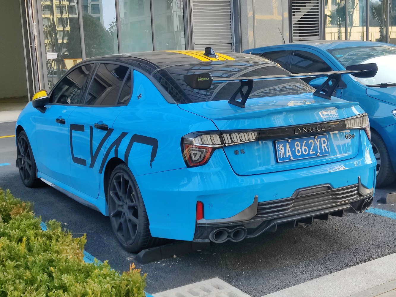 Rear of blue sedan with large racing spoiler and unique tail lights