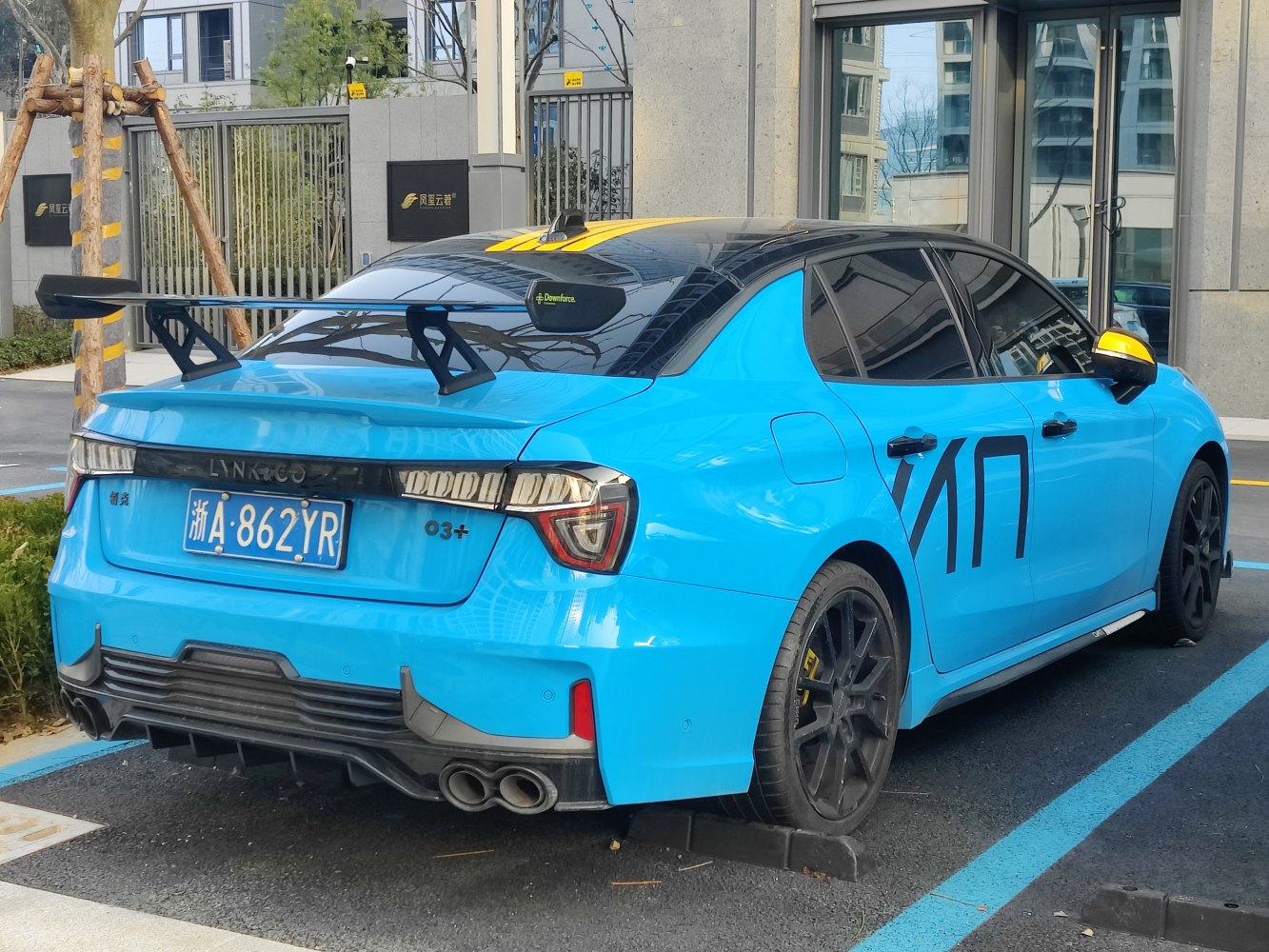 Rear view of a blue performance sedan with large rear wing and quad exhausts