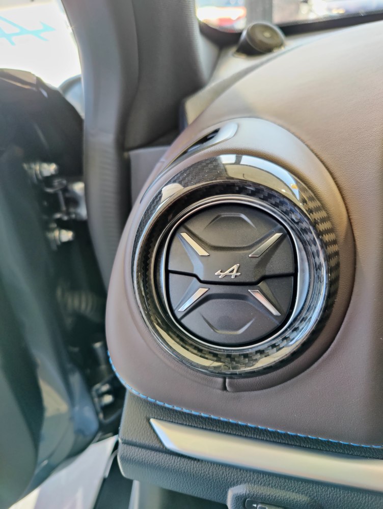 Round interior air vent with carbon fiber trim and Alpine emblem