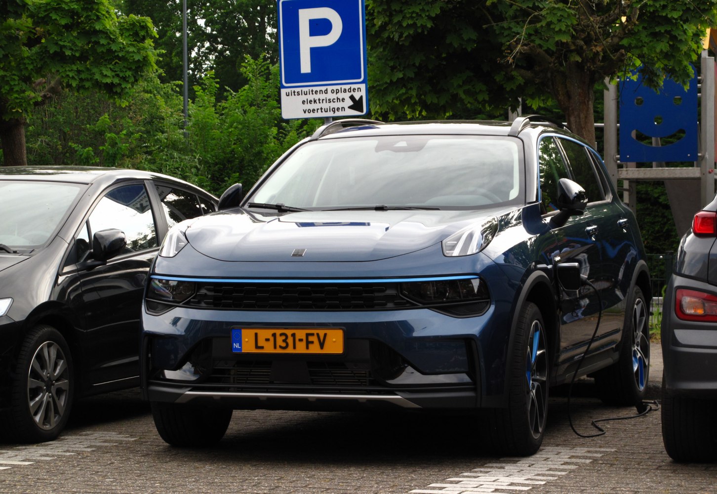 Front view of electric SUV at charging station with distinctive grille and blue trim