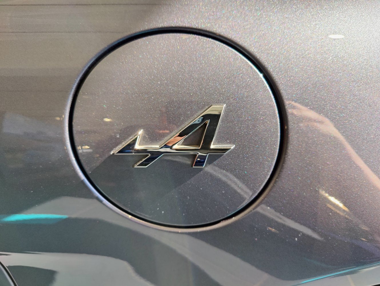 Close-up of a circular fuel cap with a chrome Alpine 'A' logo emblem.