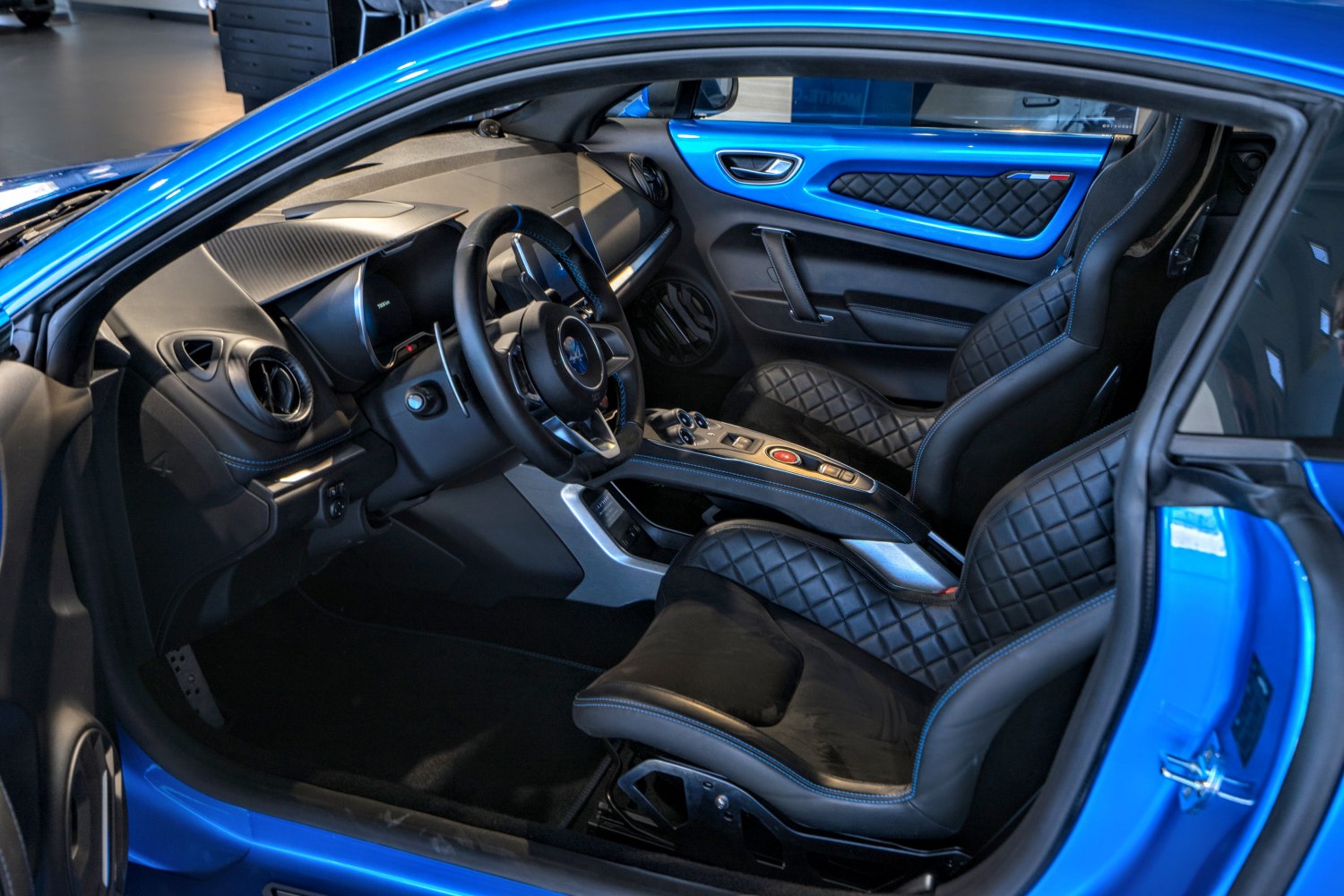 Quilted leather seats and sporty steering wheel in luxurious modern car interior.