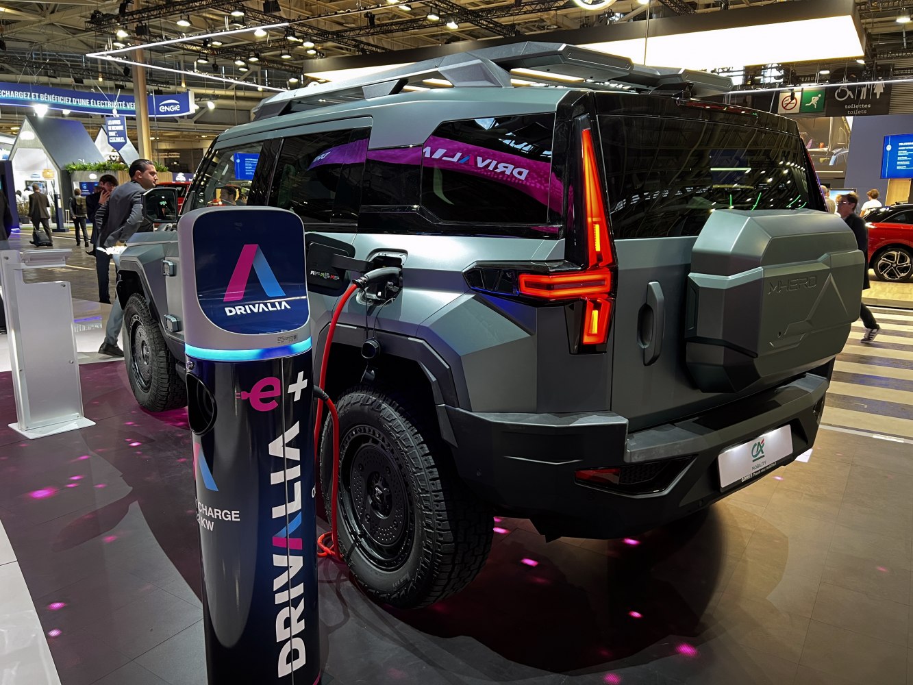 Electric SUV charging at public EV station with modern angular design and rear LED lights