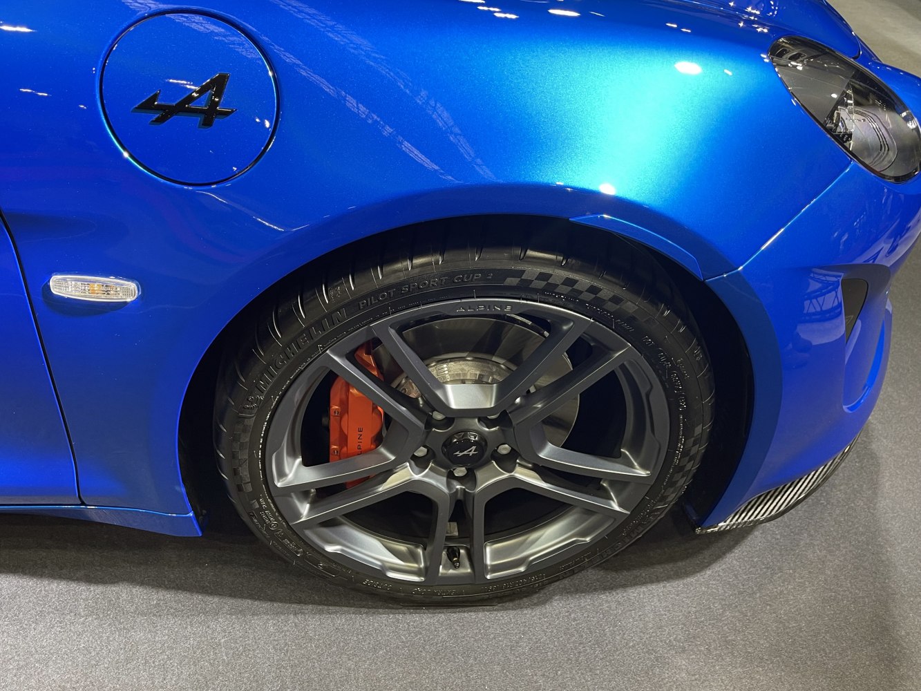 Close-up of alloy wheel with red brake caliper on blue body