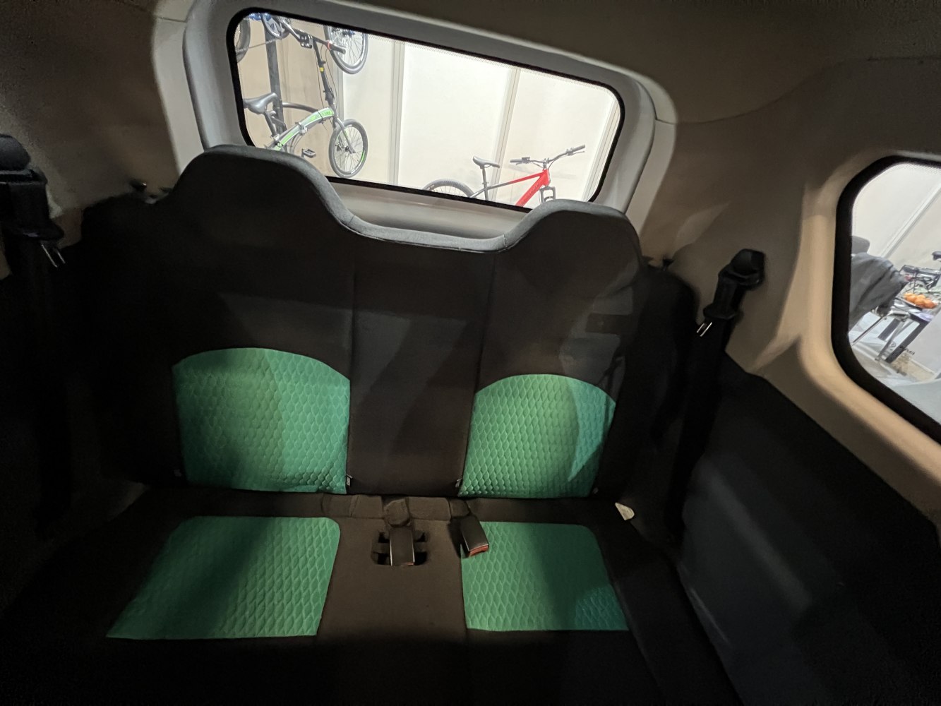Rear seating with green cushioned upholstery and seatbelt in vehicle interior
