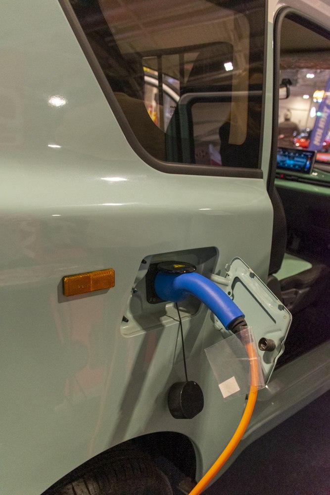 Close-up of electric charging port with cable attached on vehicle side.