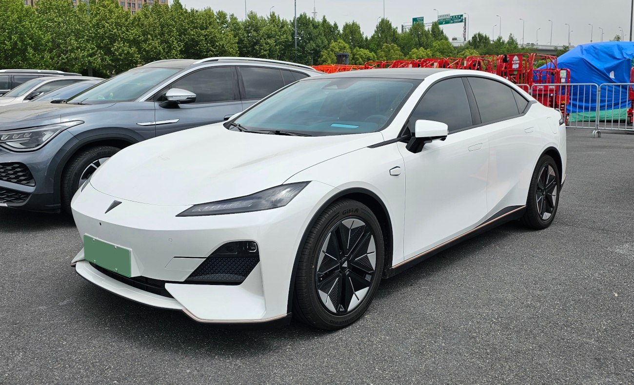 Sleek white electric sedan front and side view with aerodynamic body and modern headlights.