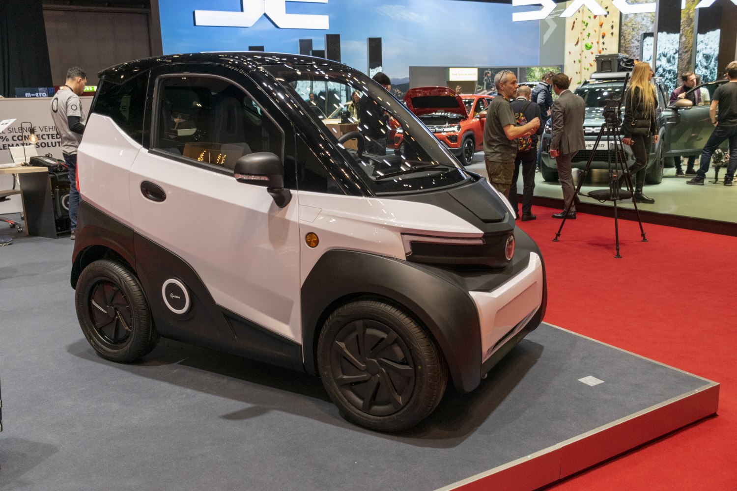 Compact electric urban vehicle with two-tone design and aerodynamic black wheels.
