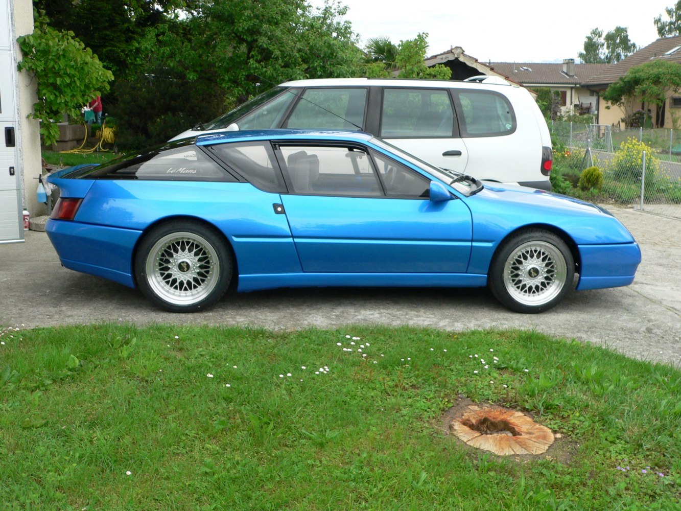 Side profile of a blue sports coupe with distinctive alloy wheels.
