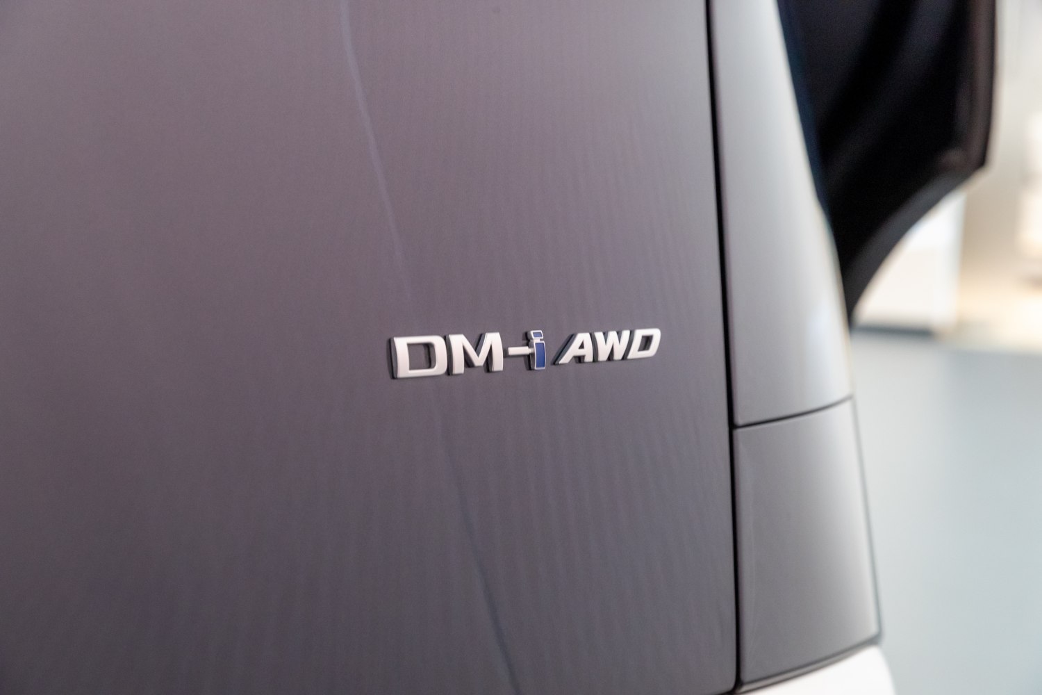 Close-up of DM-i AWD hybrid badge on vehicle surface