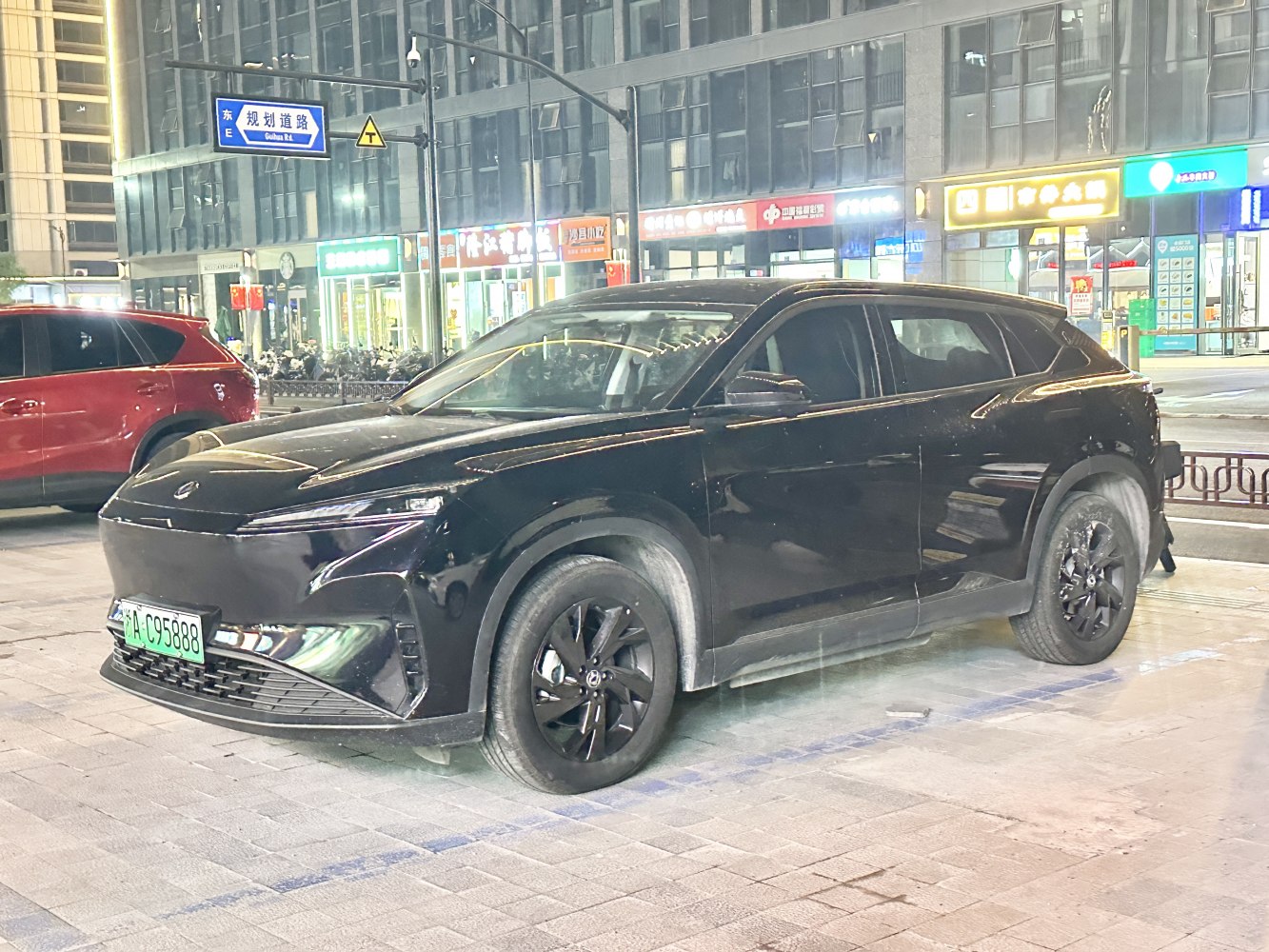 Sleek black electric crossover SUV with sharp LED front lights and aerodynamic shape.