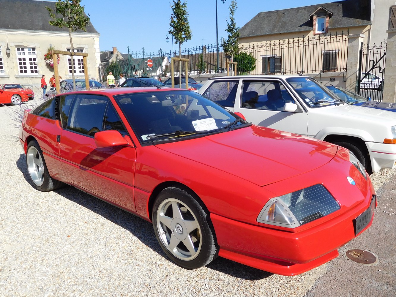 Red sports coupe with pop-up headlights and five-spoke alloy wheels