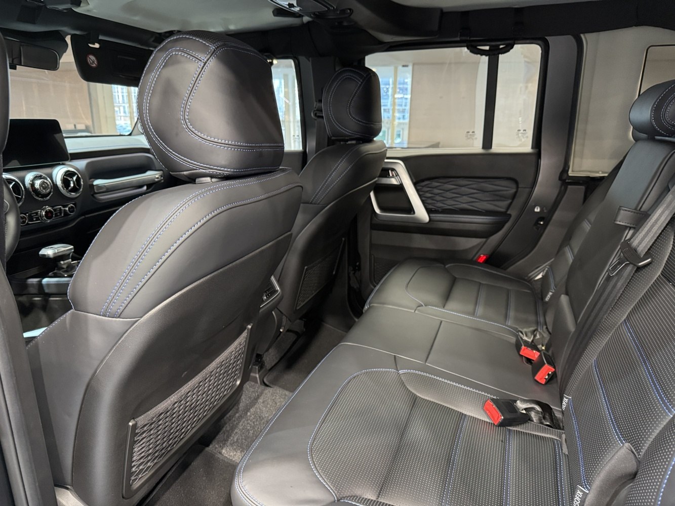 Rear car interior with black leather seats and blue stitching