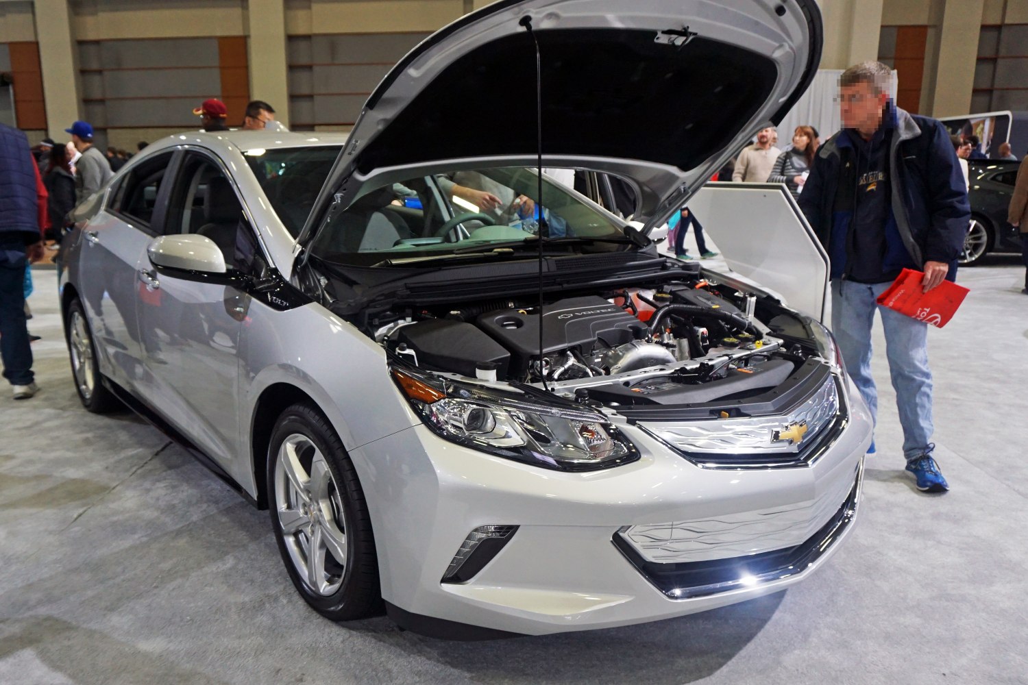 Open hood view of a silver sedan showing the engine bay and front exterior.