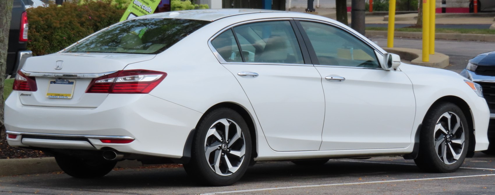 Rear side view of a white midsize sedan with distinct taillights and alloy wheels