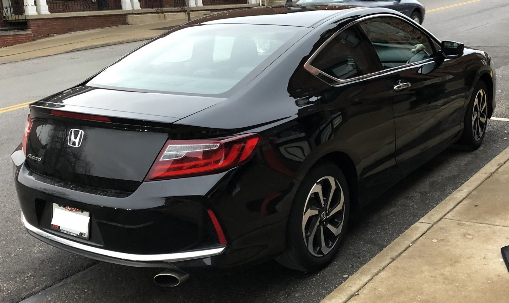 Rear view showing tail lights and exhaust pipe of a black car coupe