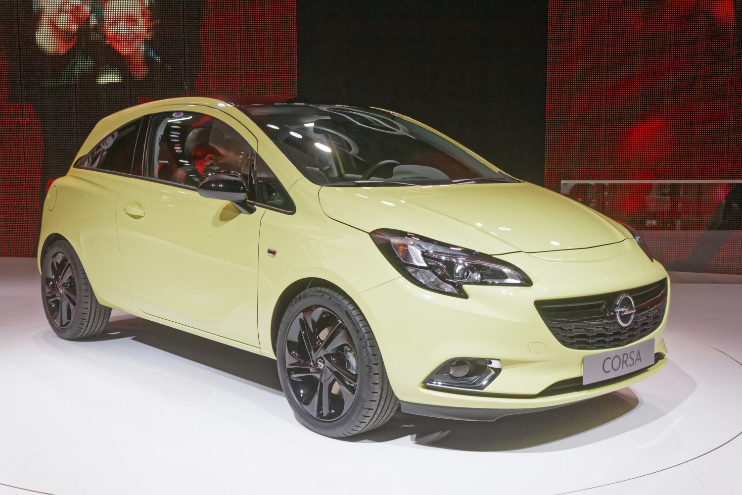 Front three-quarter view of compact hatchback with distinctive headlights and black alloy wheels.