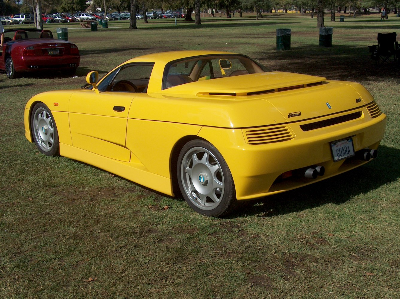 Yellow sports coupe with aerodynamic side and rear design, dual exhausts, distinctive rear venting.