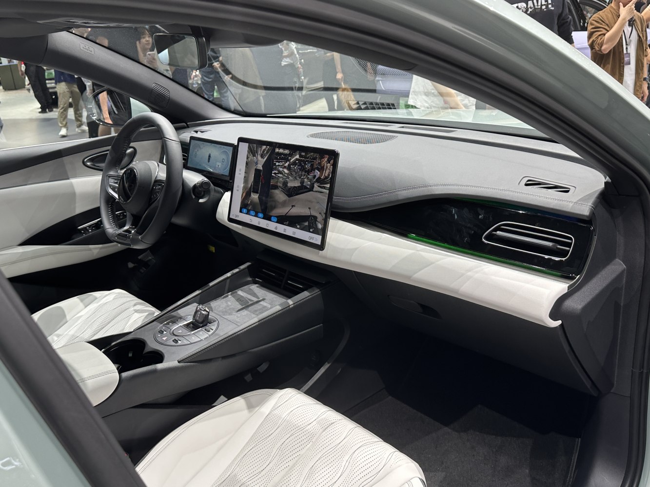 Dual digital displays and white leather seats inside a modern car interior.