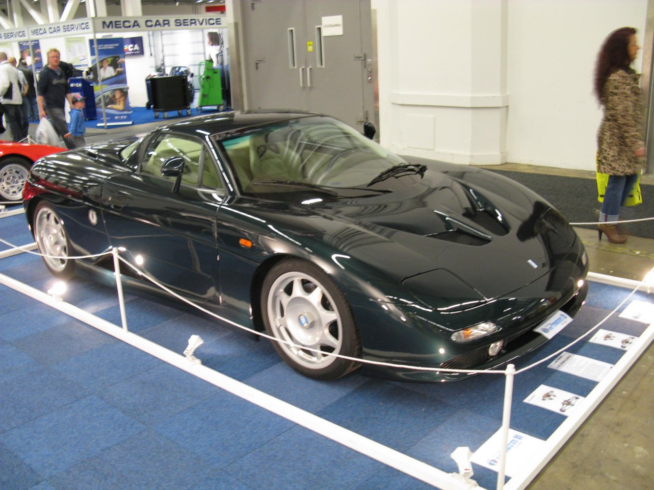 Aerodynamic black sports coupe with distinctive hood vents and alloy wheels.