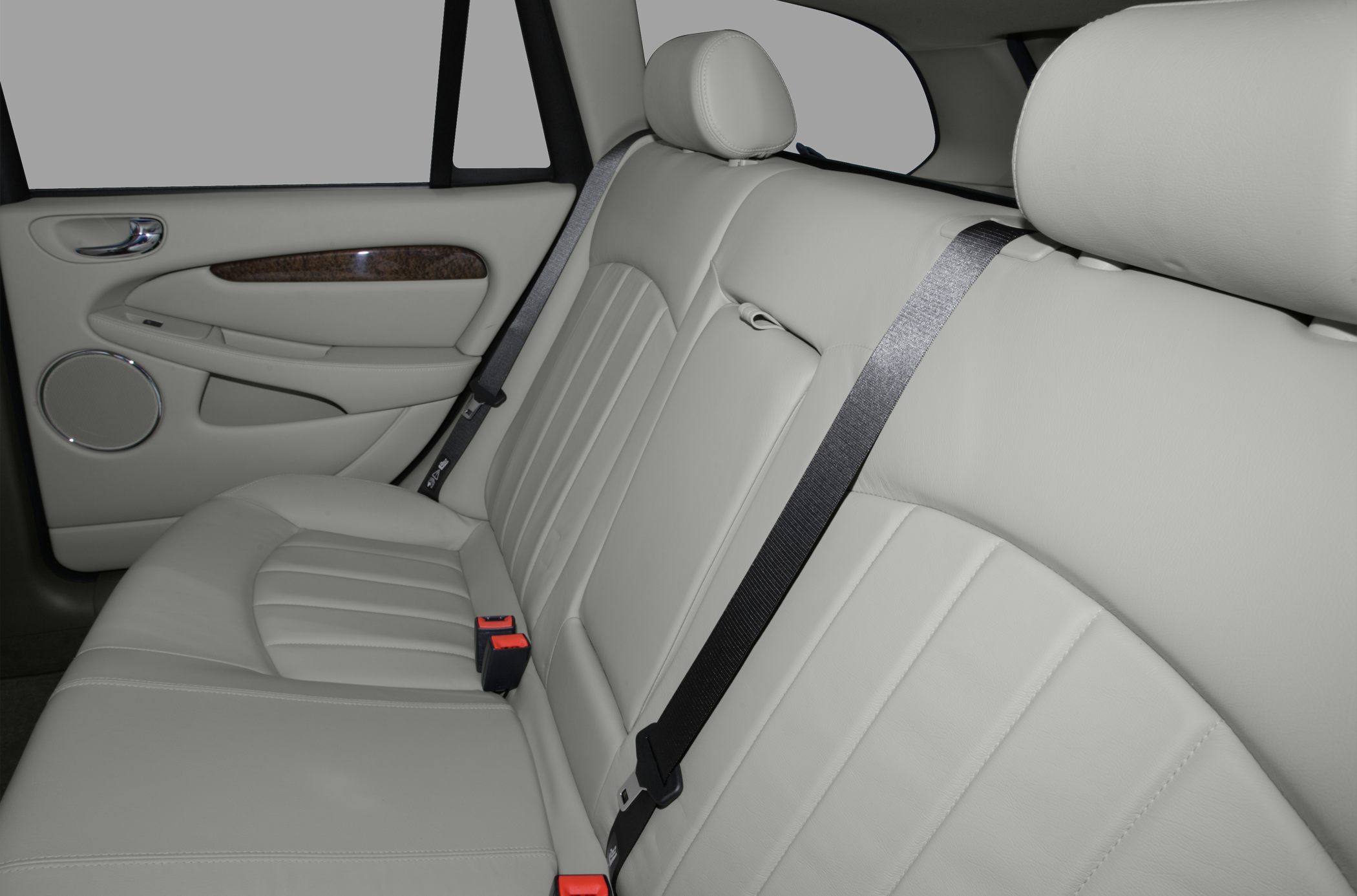 Beige leather rear seat interior with safety belts and wood trim